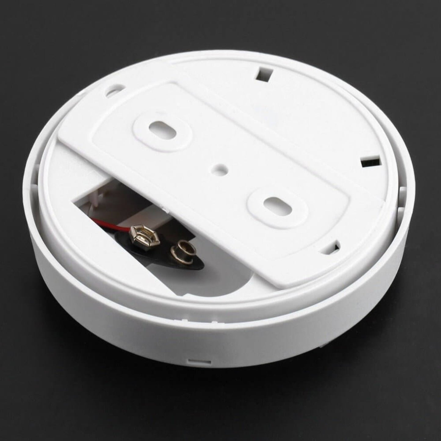 Back of a smoke alarm, showing the battery compartment and wiring for easy installation and maintenance.