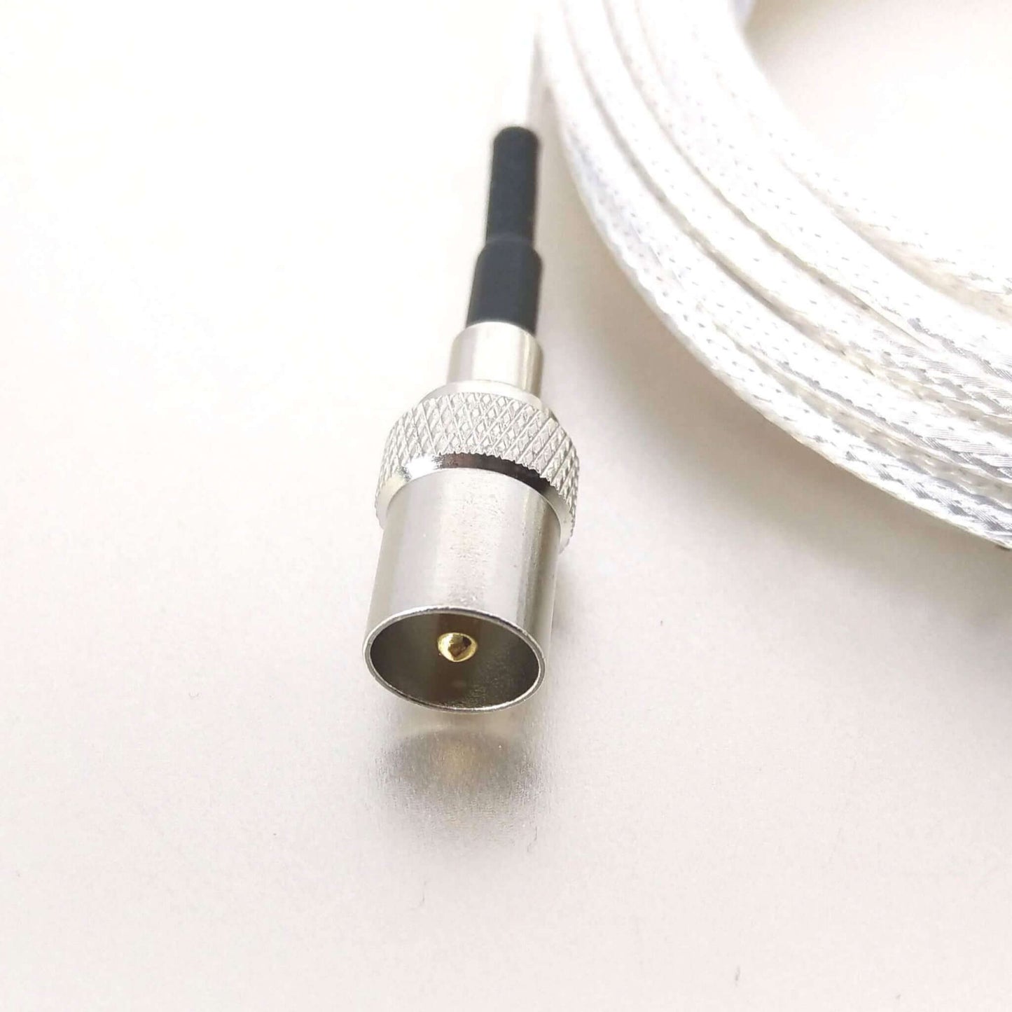 Close-up of a high-quality, straight male coaxial connector on a white antenna cable for secure connection.