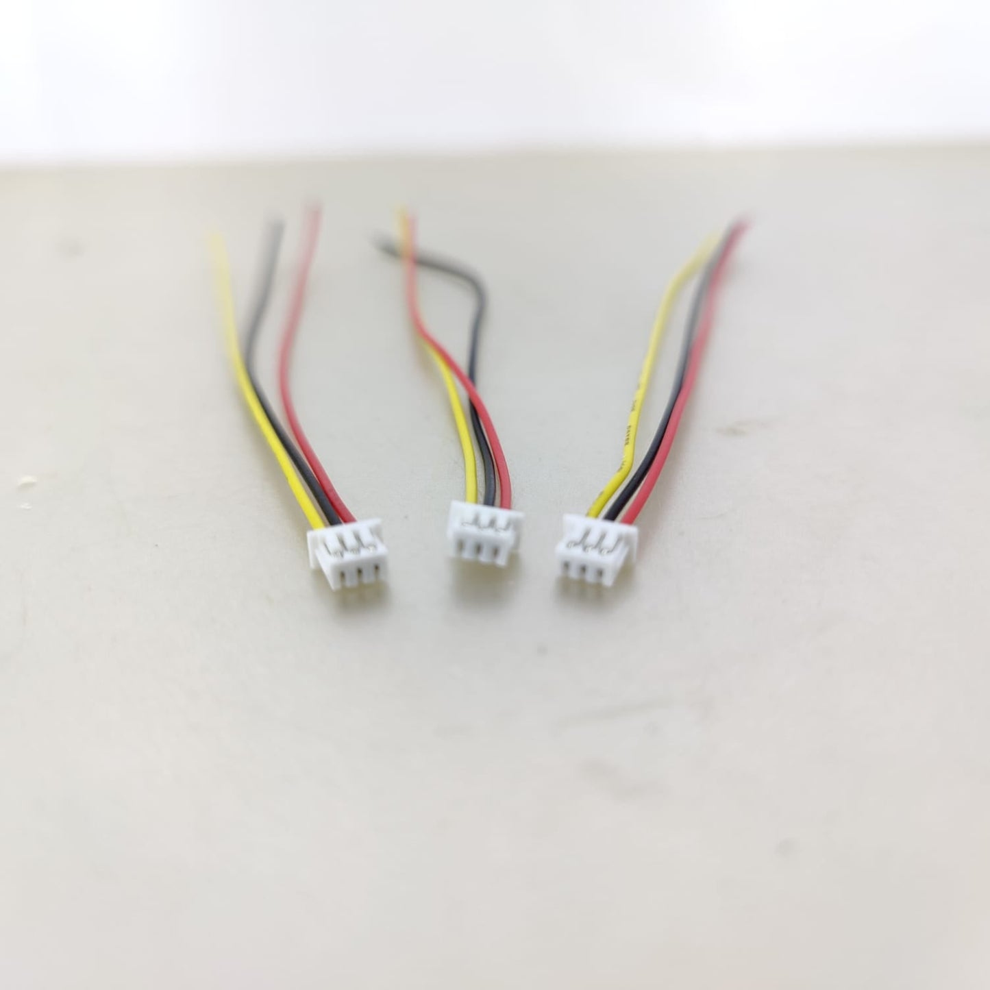 Three 1.25mm 3-pin connector wires arranged on a workbench, ready for a DIY project.