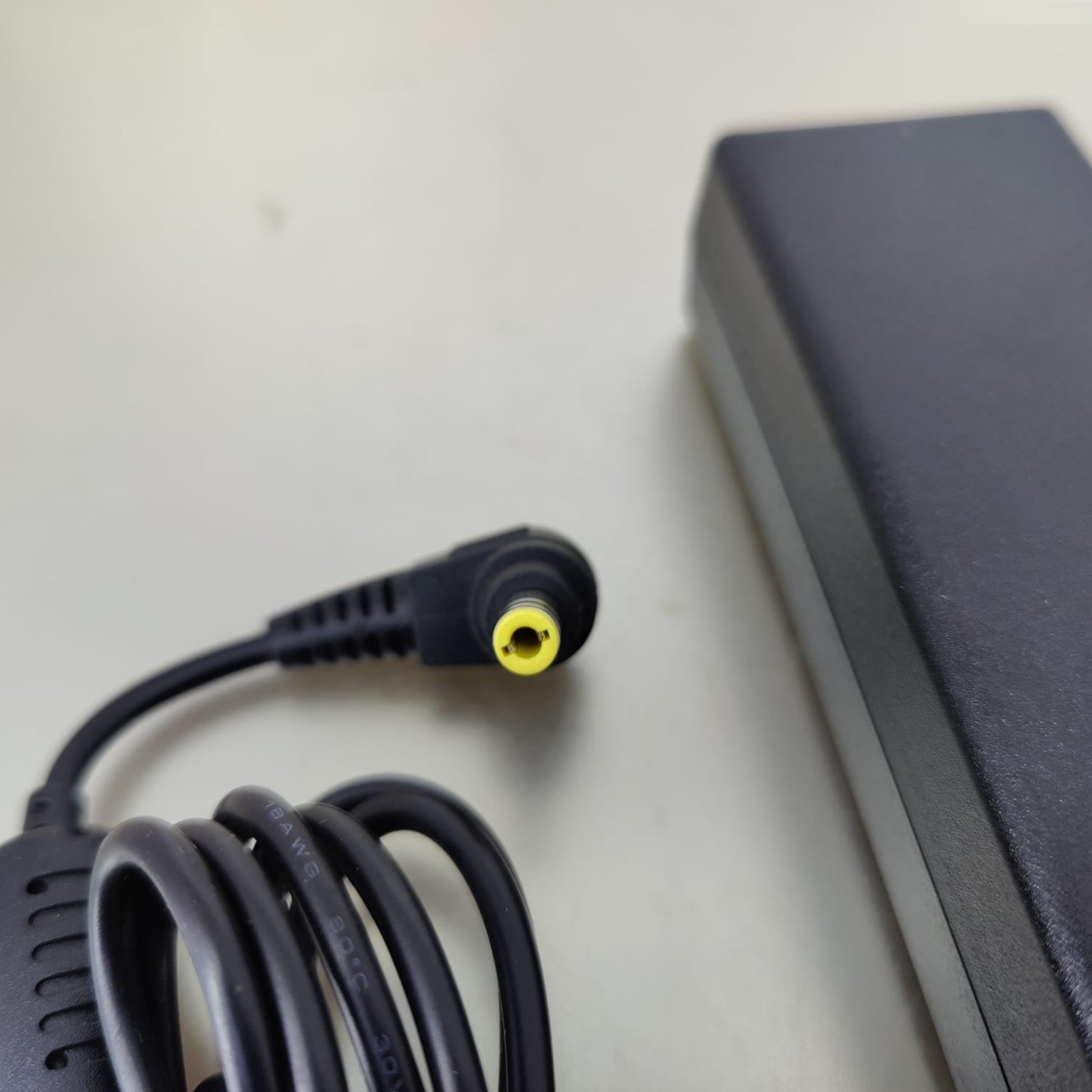 Close-up of the 5.5mm by 2.5mm right-angle barrel connector with a yellow tip for Fujitsu laptops.
