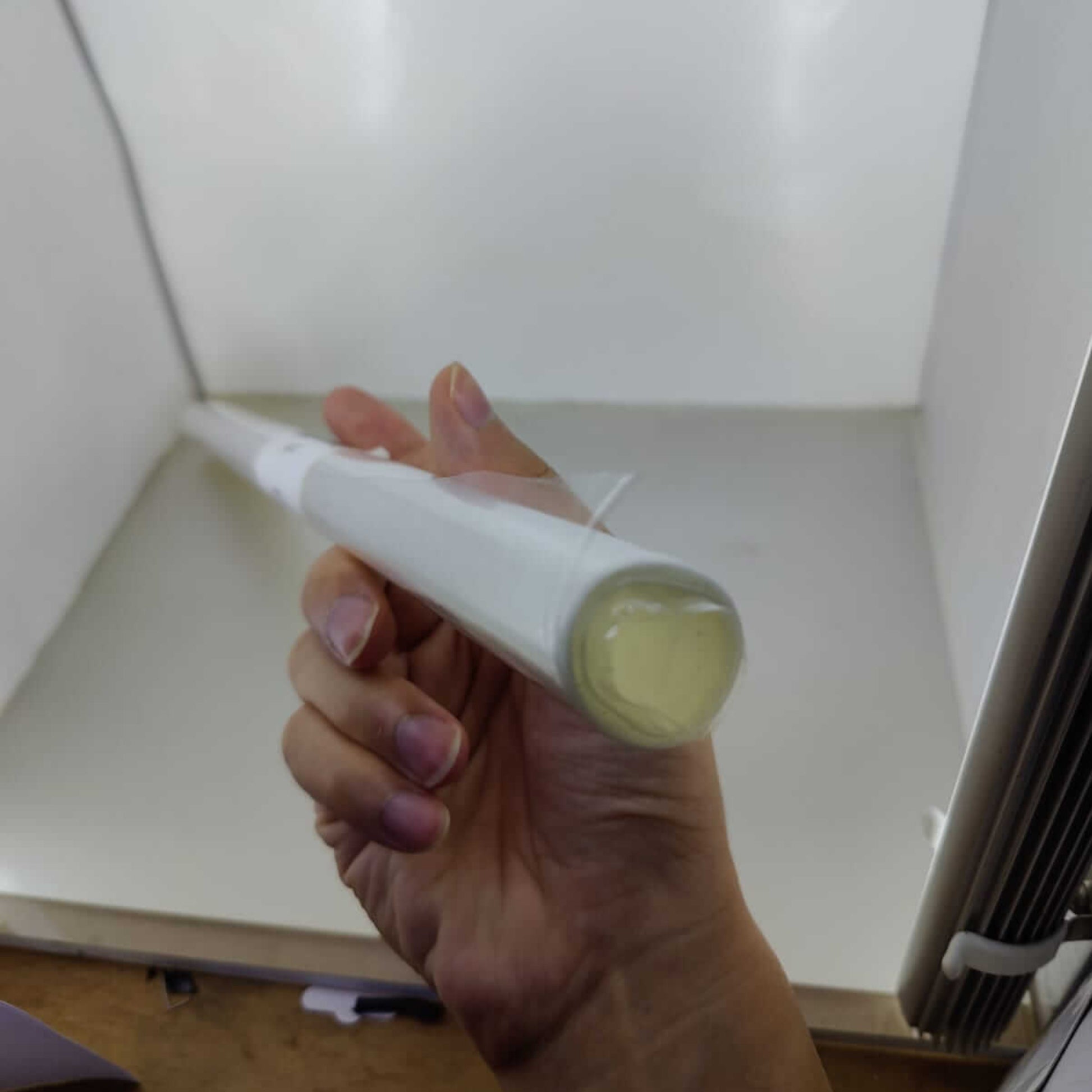 Hand holding a roll of heat shrink wrap film, ideal for gift and product packaging, inside a photo studio.