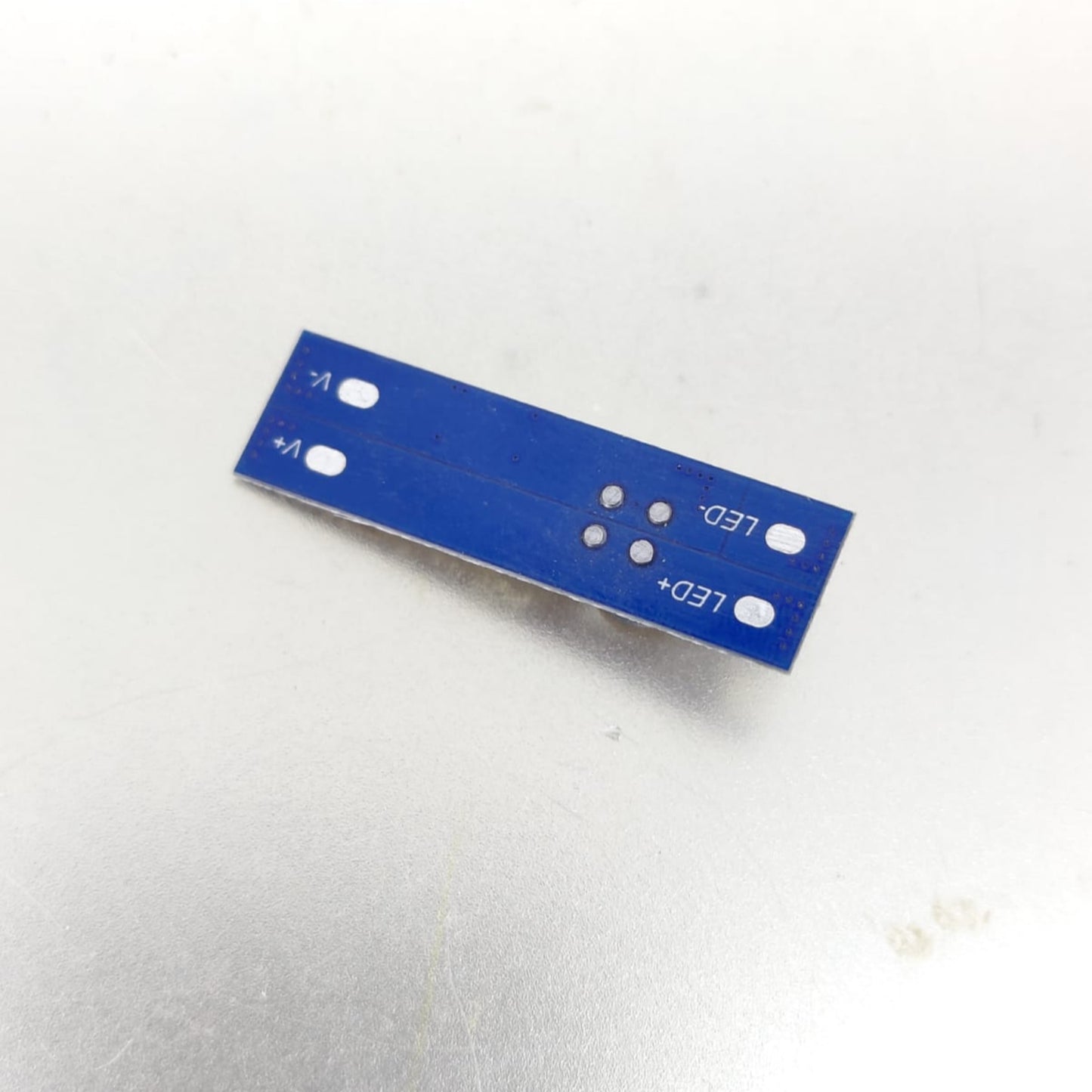 Close-up of a blue circuit board for LED connections with labeled terminals.