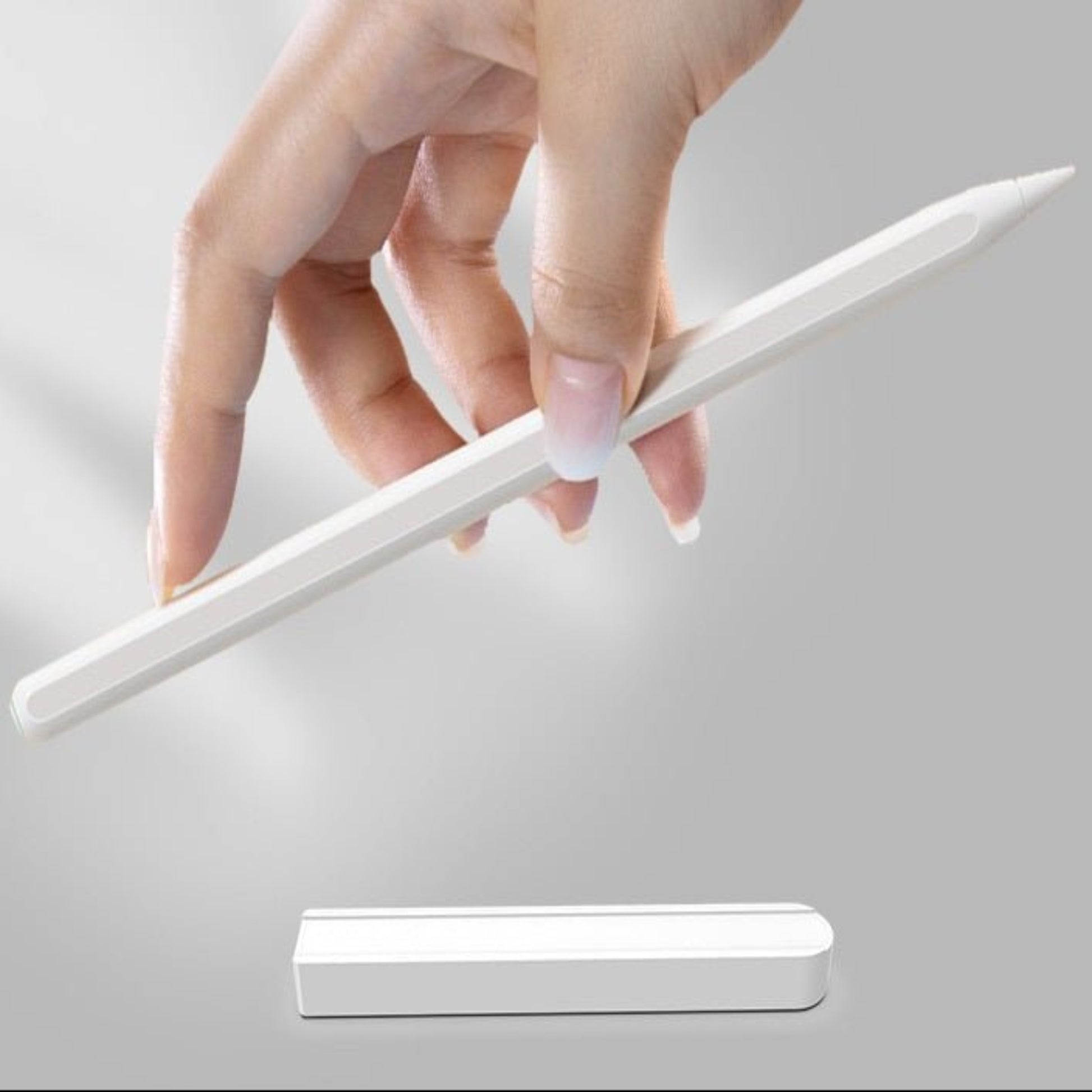 Hand holding Apple Pencil 2 above a magnetic charging adapter cable, showcasing the convenient charging method.