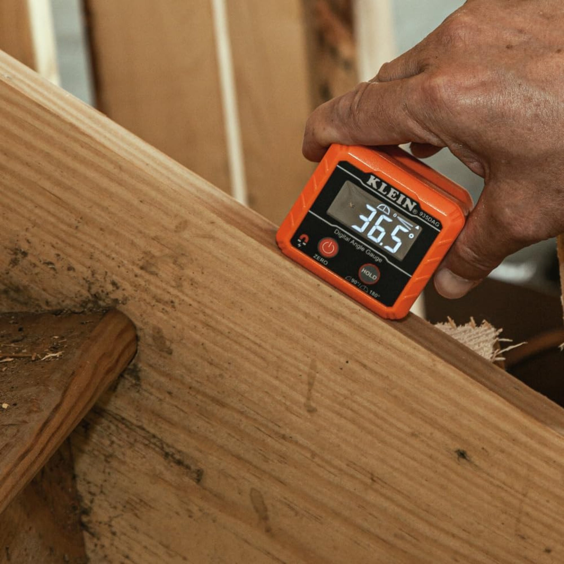 Carpenter checking wood angle with Klein Tools digital electronic level.