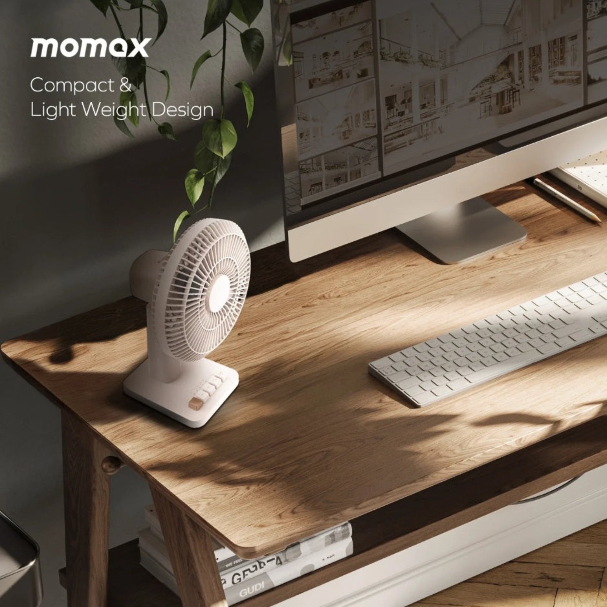 Momax 1°Pod fan sitting on a modern wooden office workspace next to a computer monitor and keyboard.