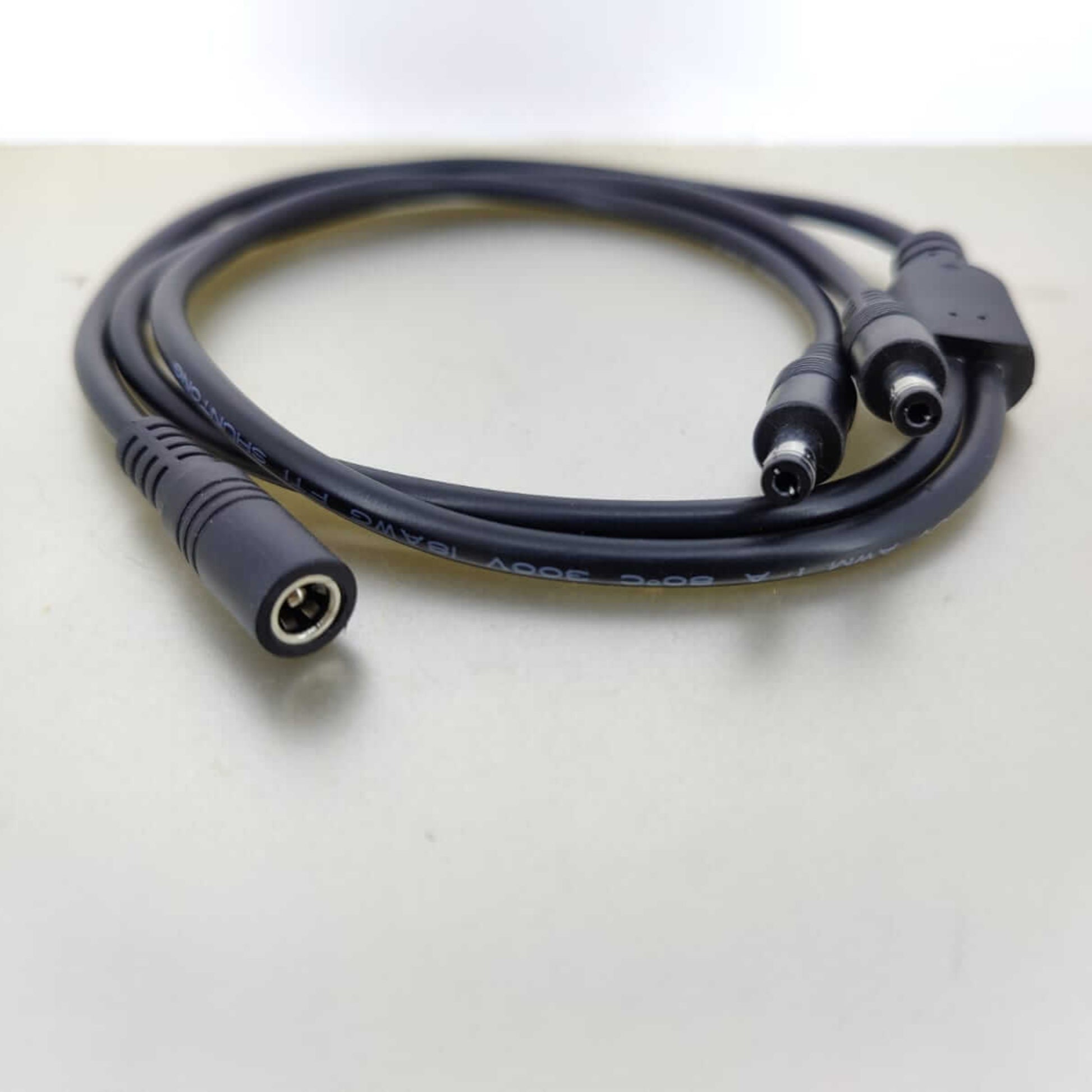 DC power cable splitter with one female 5.5mm x 2.1mm connector and two male connectors.