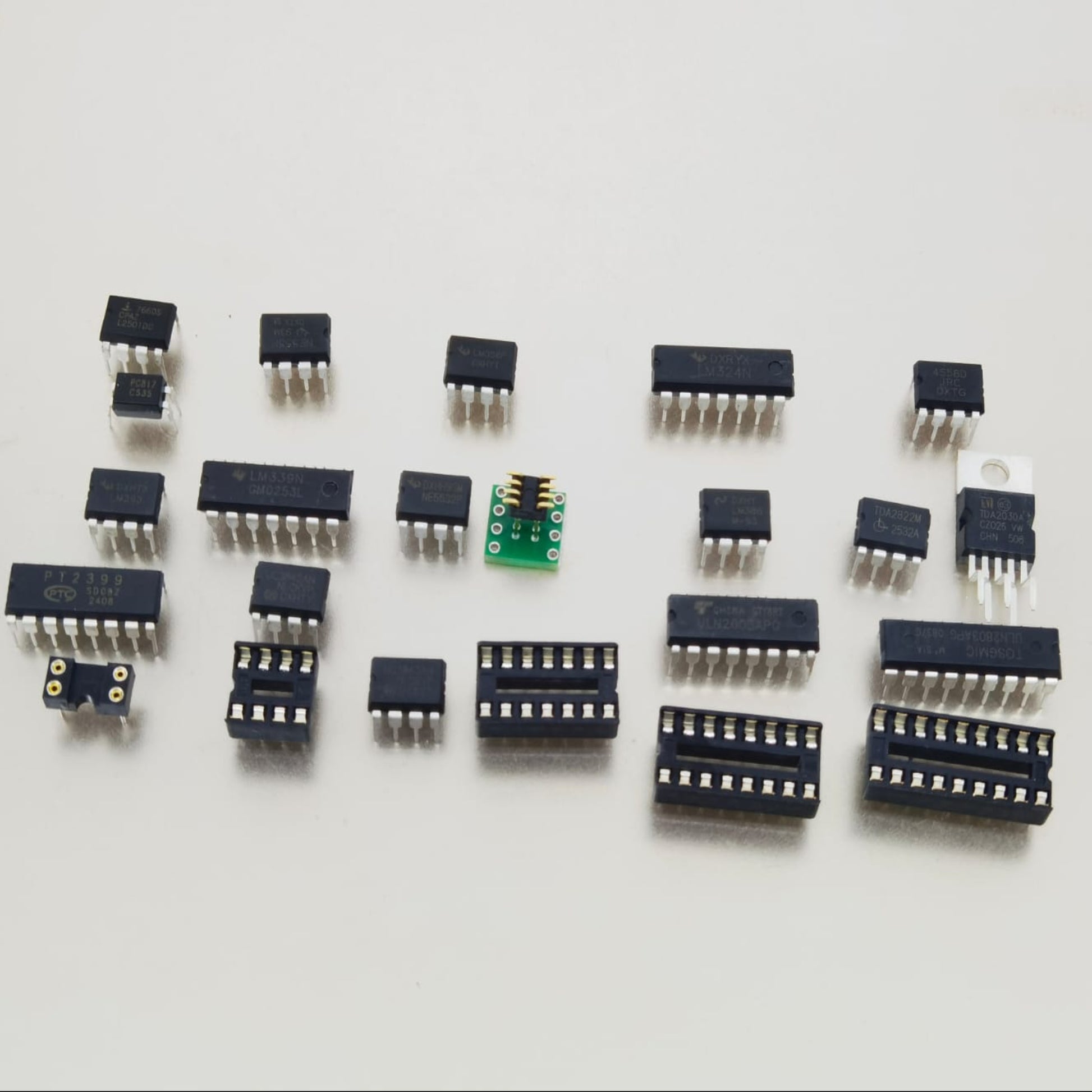 Close-up display of loose IC chips including TDA2030A, ULN2003AN, and DIP sockets on a white background.