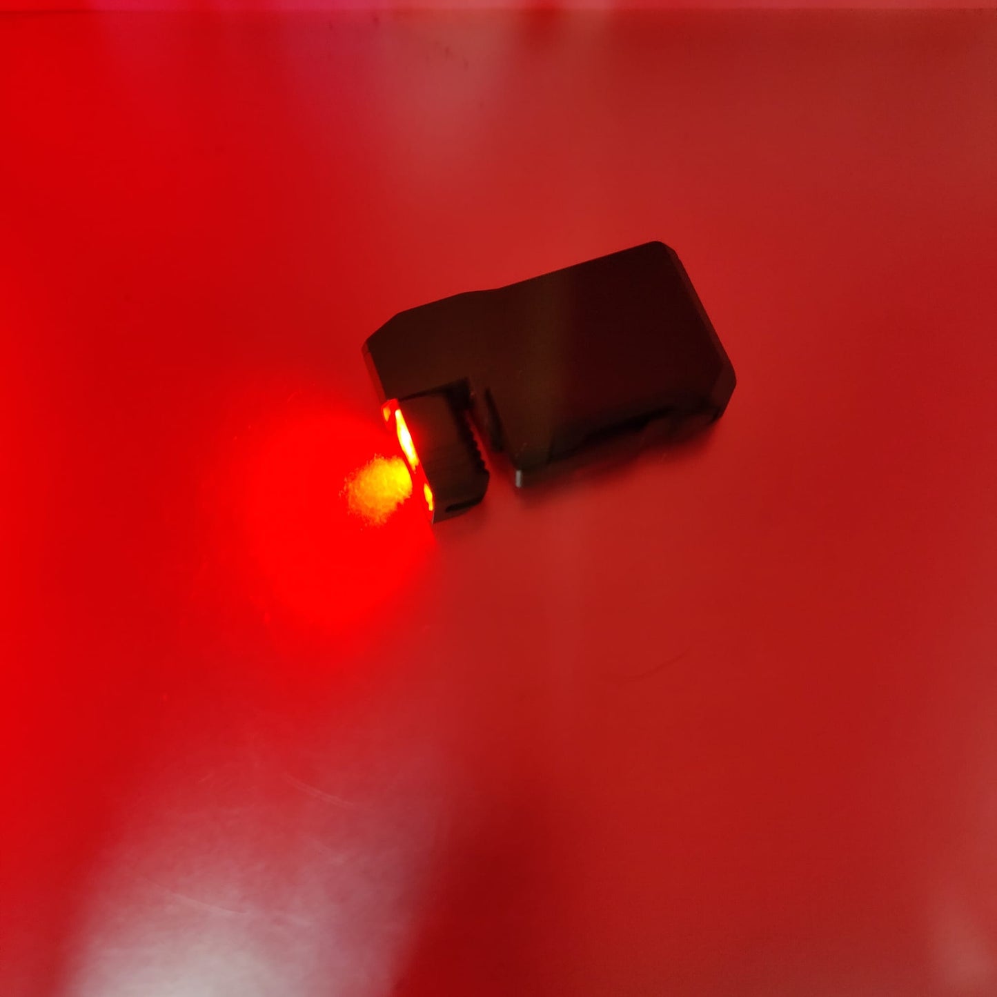 The tactical black EDC mini flashlight illuminating a dark room with its red light mode.