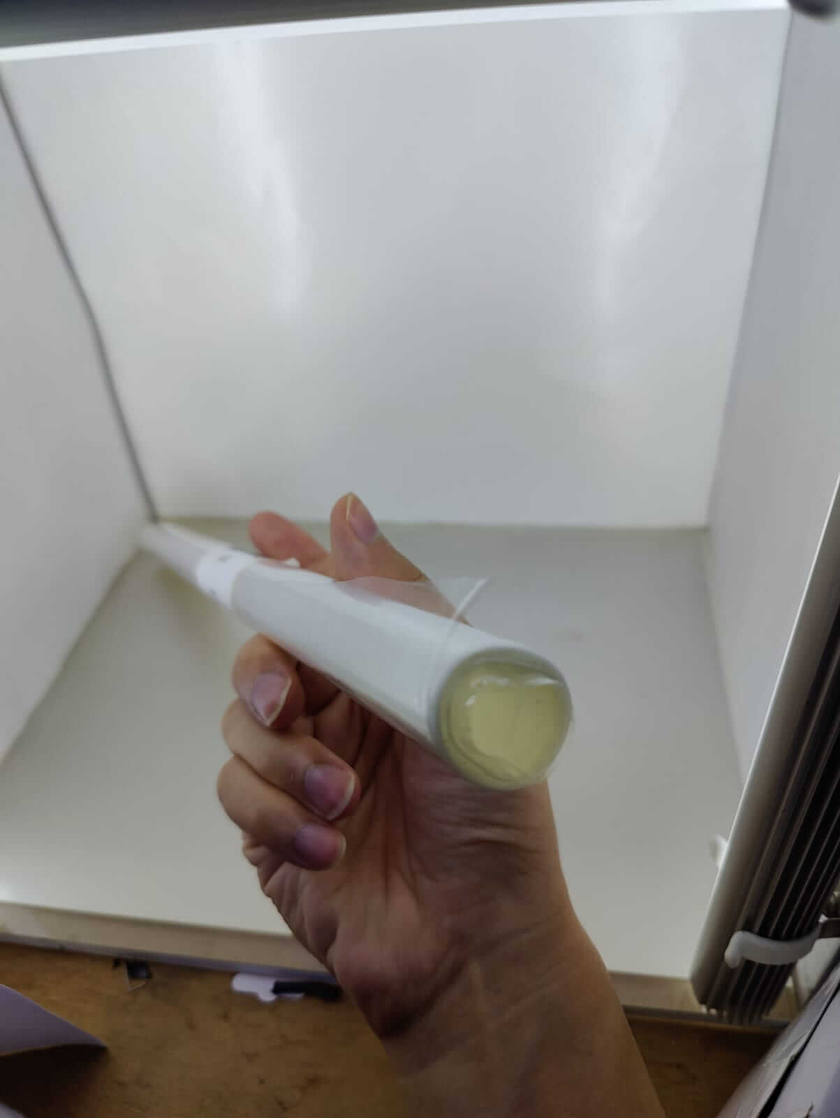 Hand holding a roll of heat shrink wrap film, ideal for gift and product packaging, inside a photo studio.