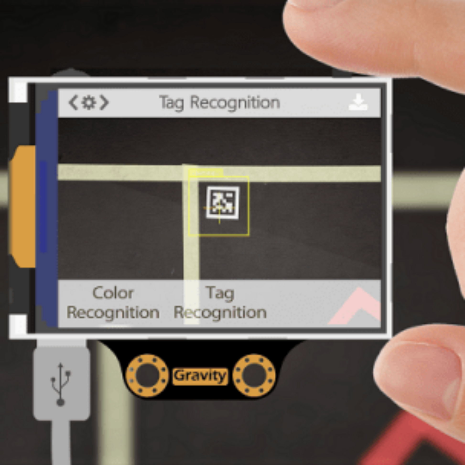 Hand holding Gravity Huskylens AI sensor showing tag recognition and color recognition features on the screen.