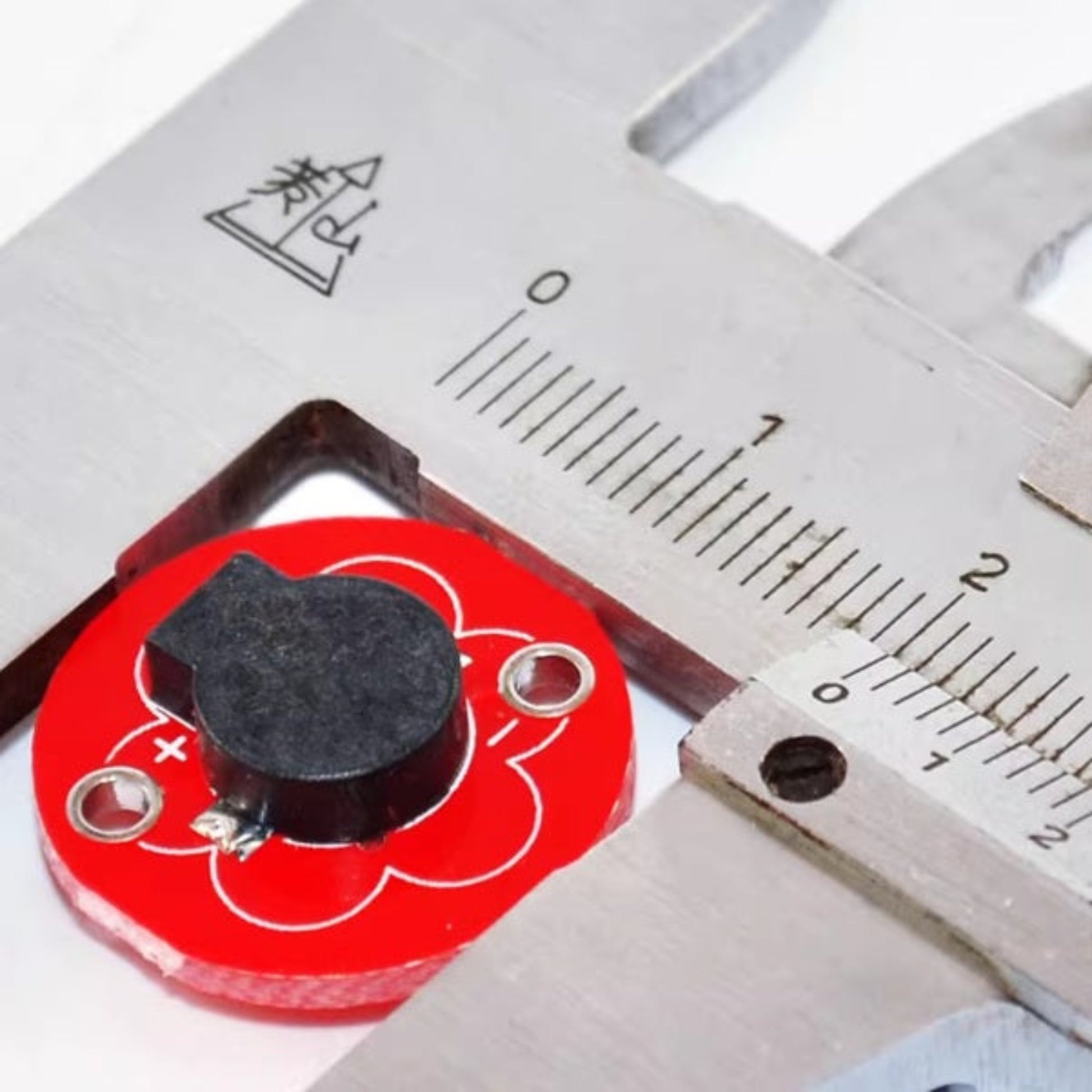 The KEYES LilyPad Buzzer Module being measured with digital calipers to show its size.