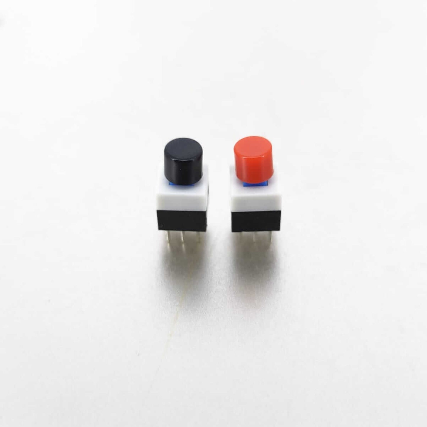 Two tactile mini push button switches with red and black caps, 8x8mm size, ideal for PCB layout in electronic devices.