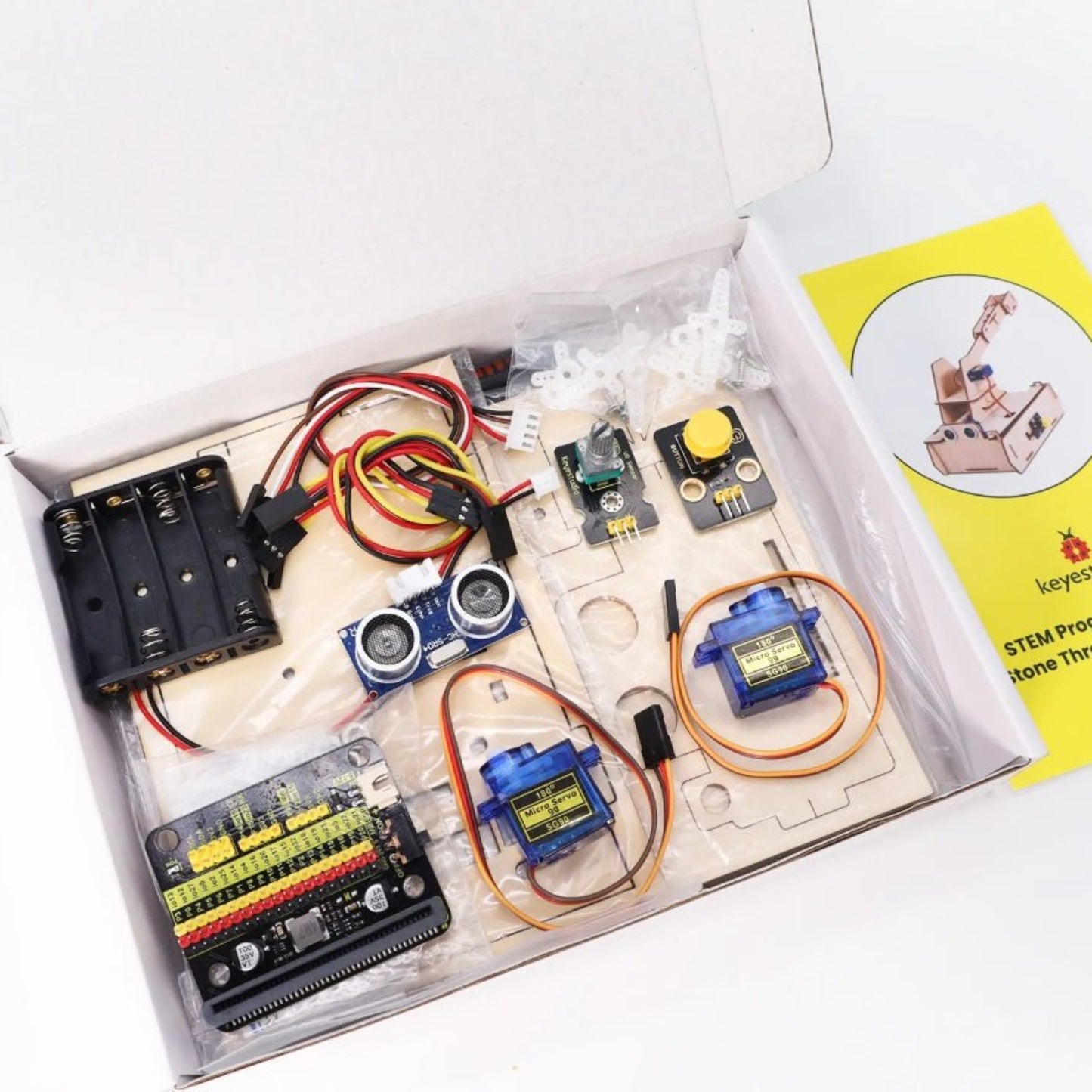 Keyestudio KS0807 micro:bit Thrower Learning Kit components in a box, featuring motors, sensors, and assembly materials.