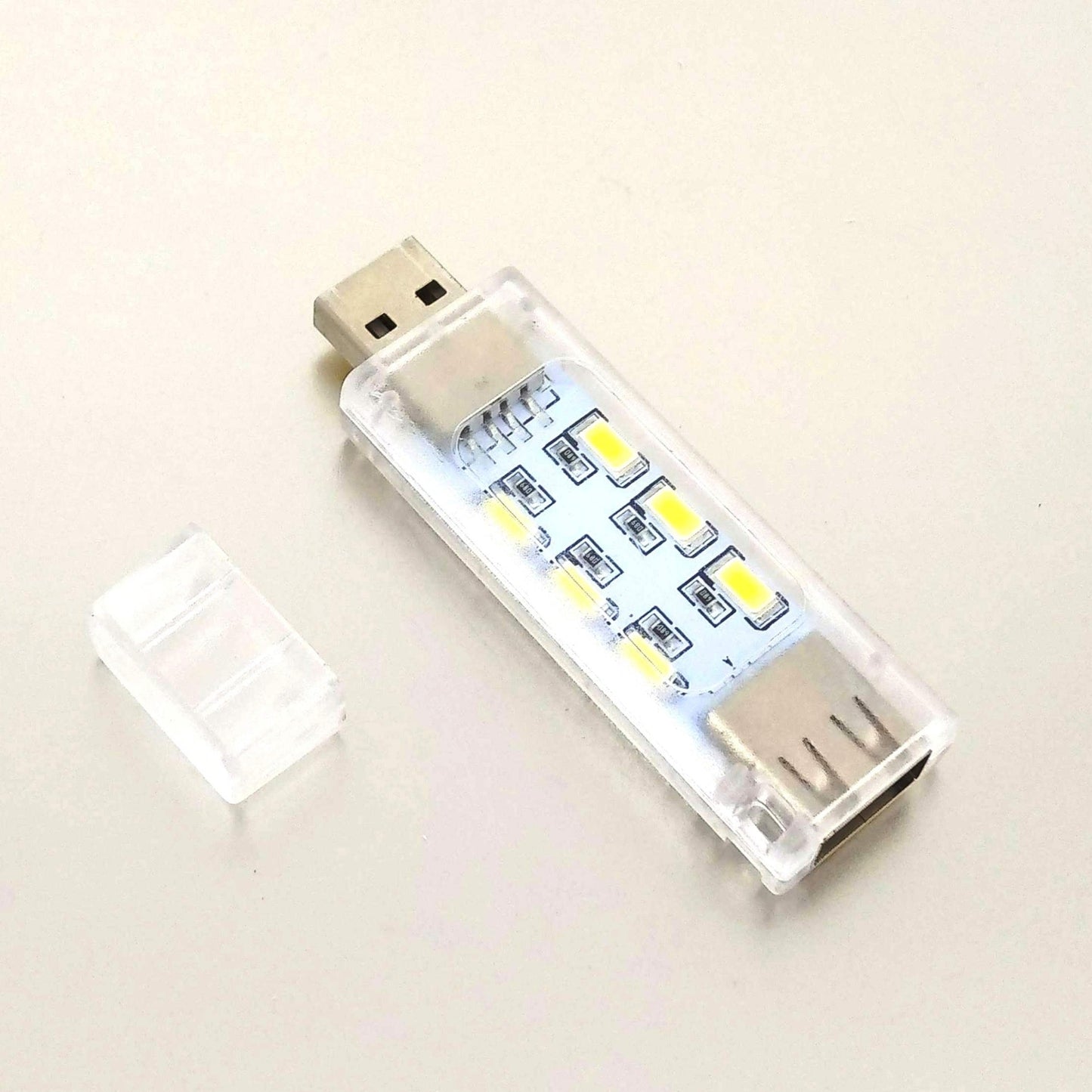 A single mini portable USB LED light with 12 LEDs shown next to its clear protective cap on a white background.