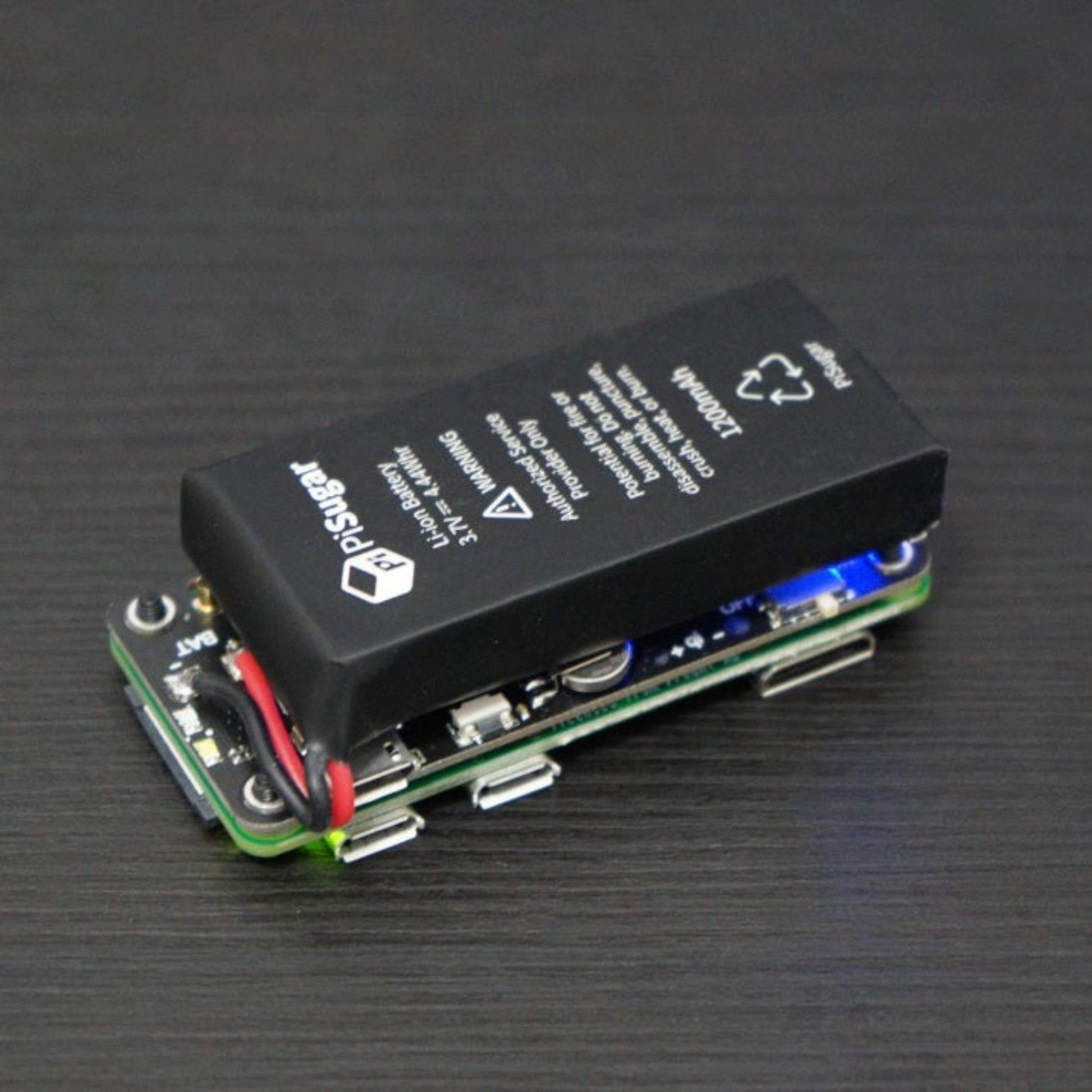 Side profile angle of the fully assembled PiSugar2 battery module demonstrating its compact form factor and active blue indicator light.