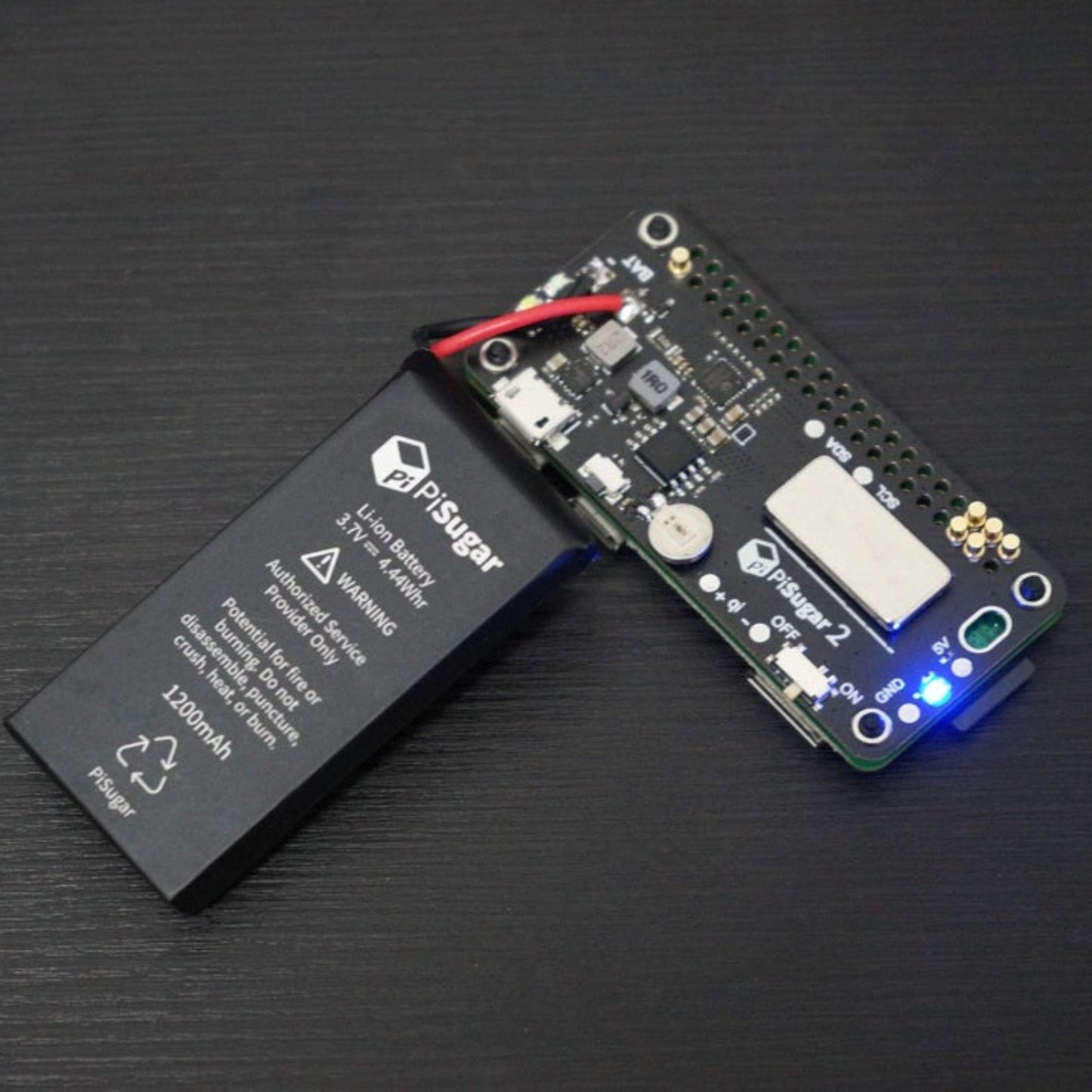 The 1200mAh lithium battery cell folded back to reveal the internal PiSugar2 printed circuit board and surface-mounted components.