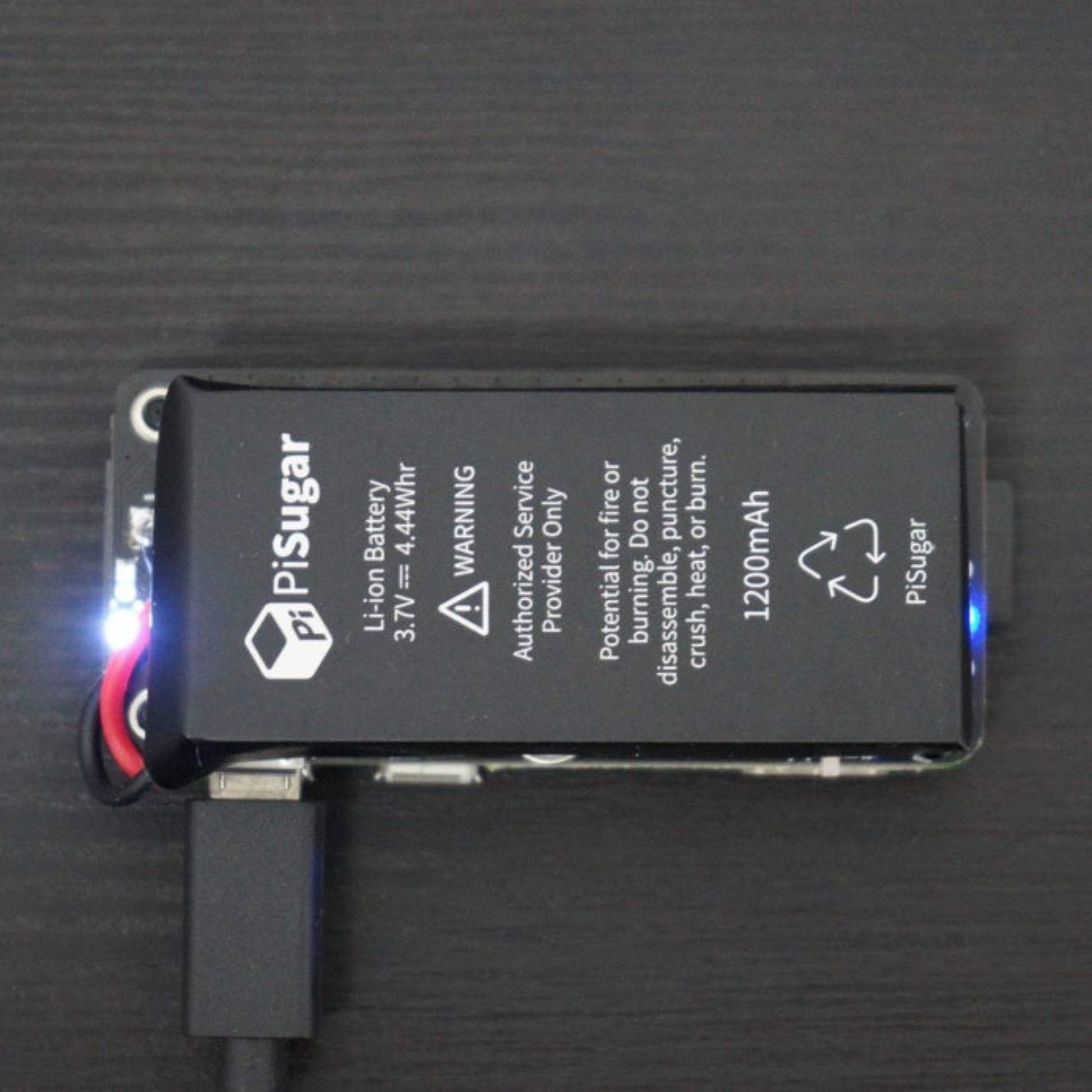 Close-up of the PiSugar2 lithium battery pack highlighting the 1200mAh capacity, warning labels, and illuminated LED status light.