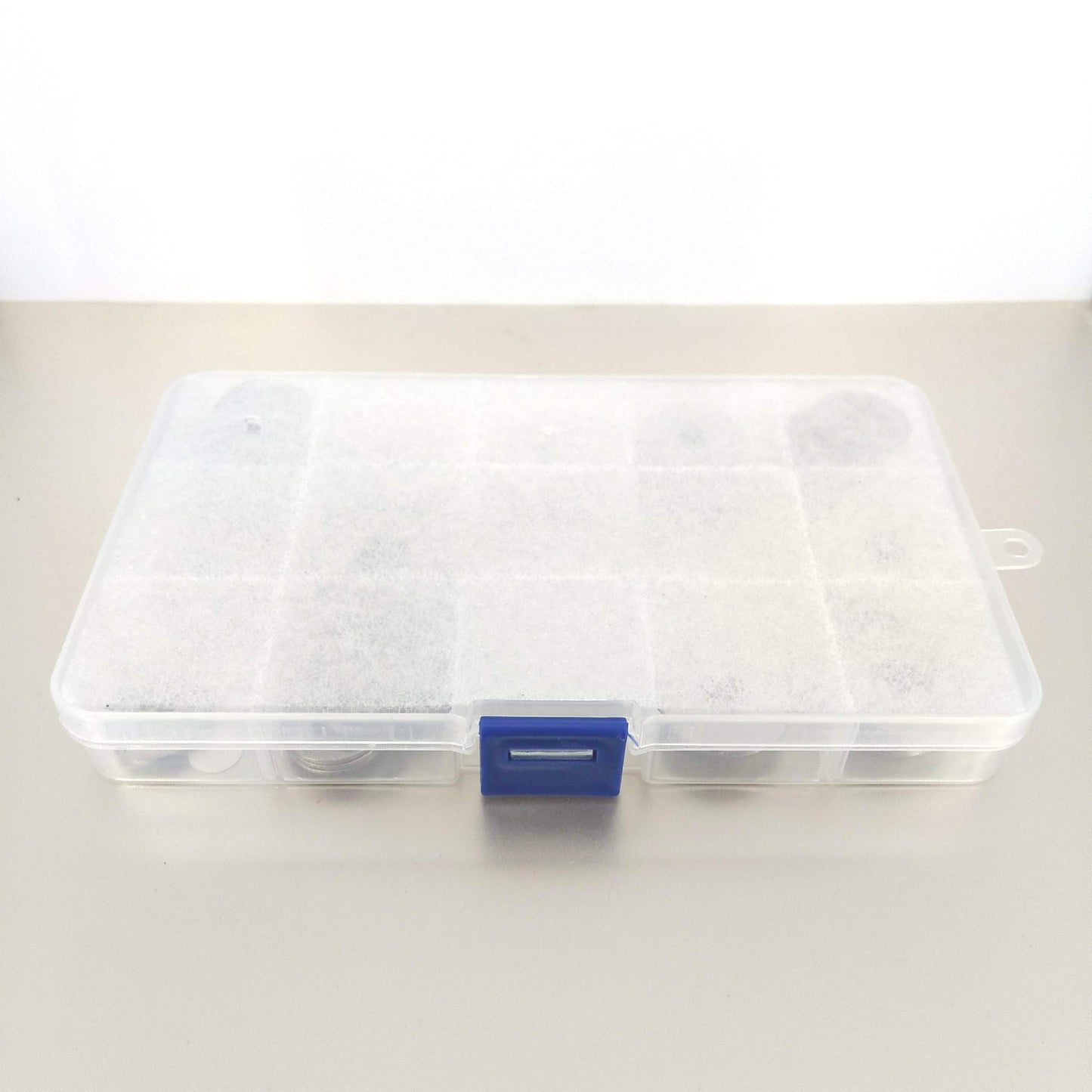 Closed transparent storage box containing stainless steel hardware washers.