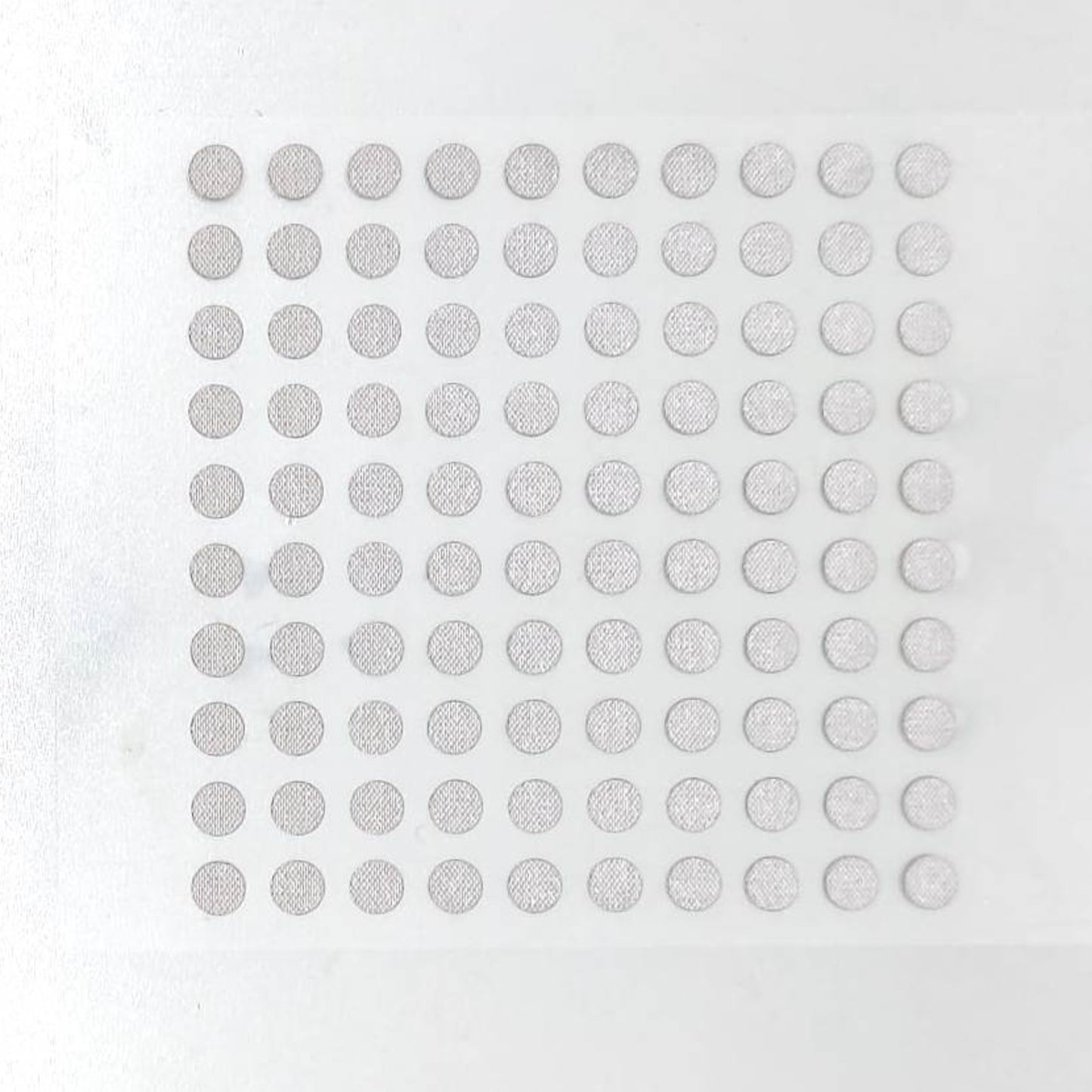 Top view of a sheet containing 100 silver conductive repair dots for remote controls.