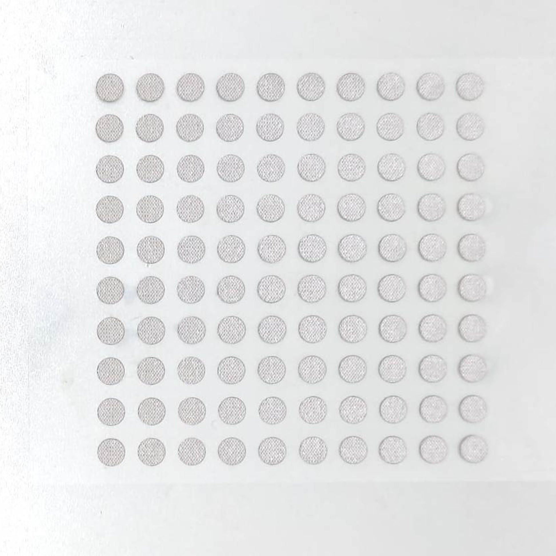 Top view of a sheet containing 100 silver conductive repair dots for remote controls.