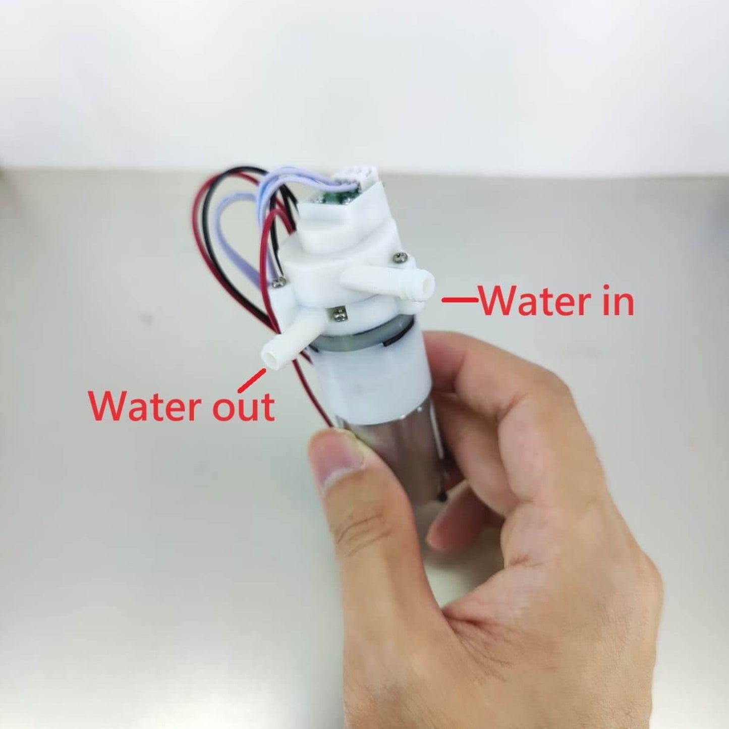 Mini DC12V water pump showing water inlet and outlet connections, ideal for compact applications.