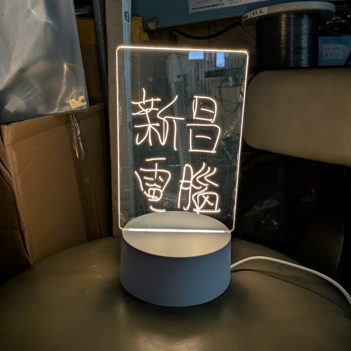 於較暗環境下發光的LED三色留言板夜燈，清晰顯示新昌電腦字句，適合電競房或書檯擺設。