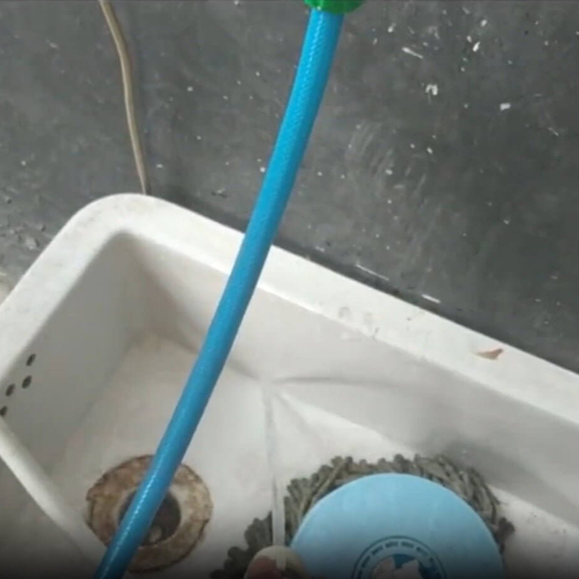 Universal faucet adapter connected to a blue hose over a sink with a mop and bucket underneath.