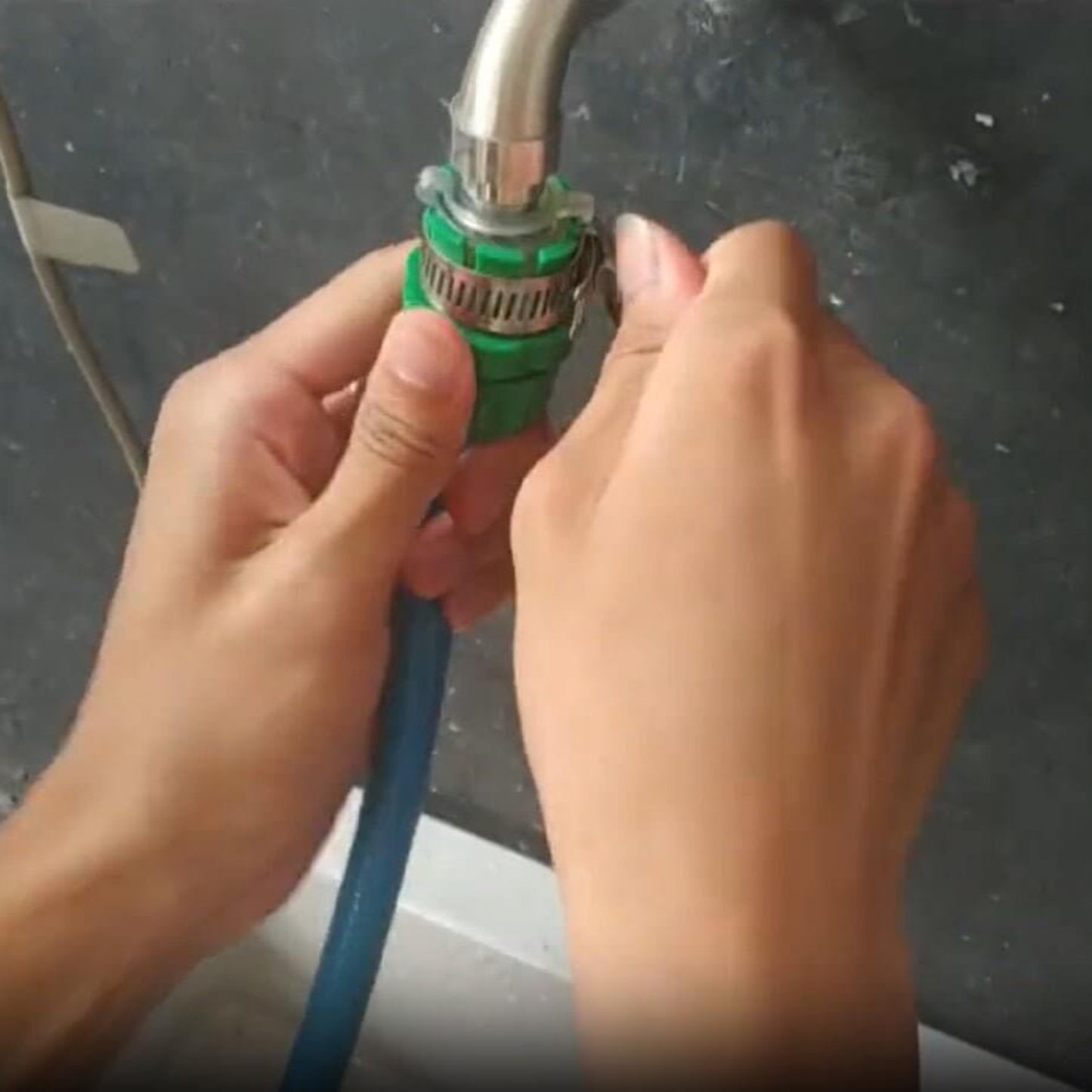 Person attaching a universal faucet adapter to a garden hose for irrigation and water supply.