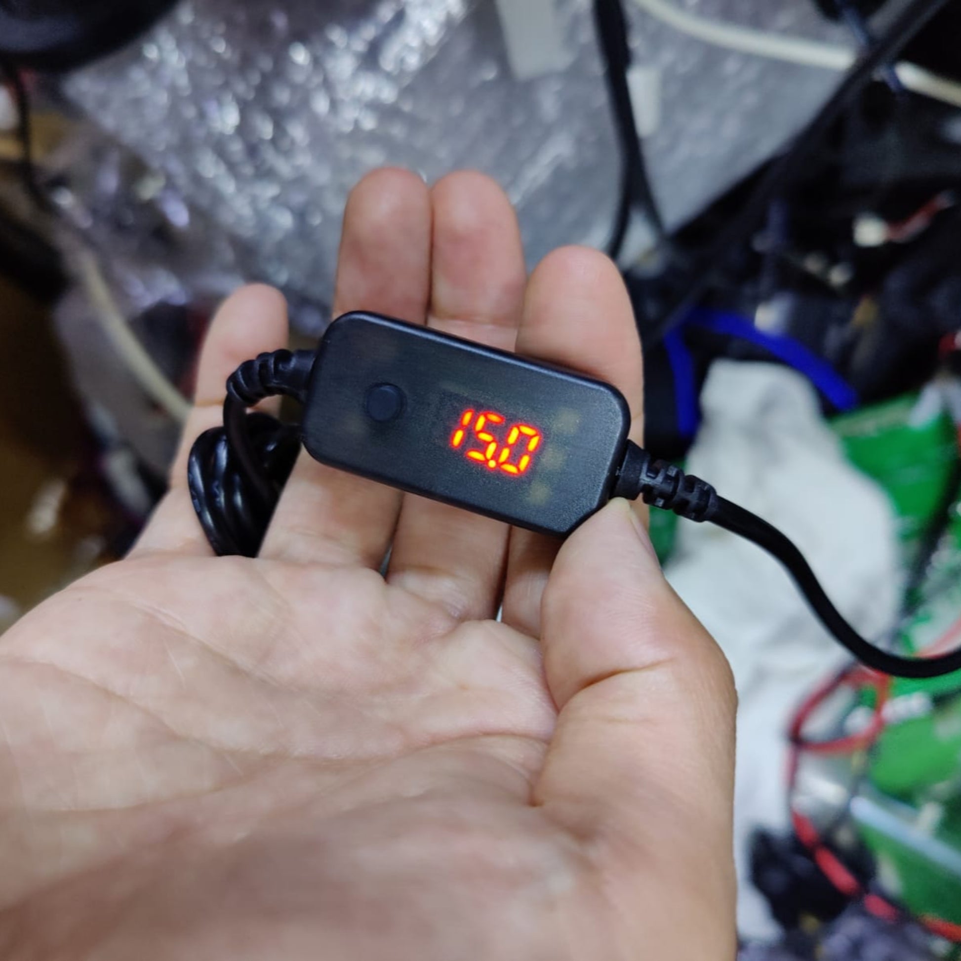 Hand holding a USB-C to DC plug cable with a digital voltage display reading 15.0V.