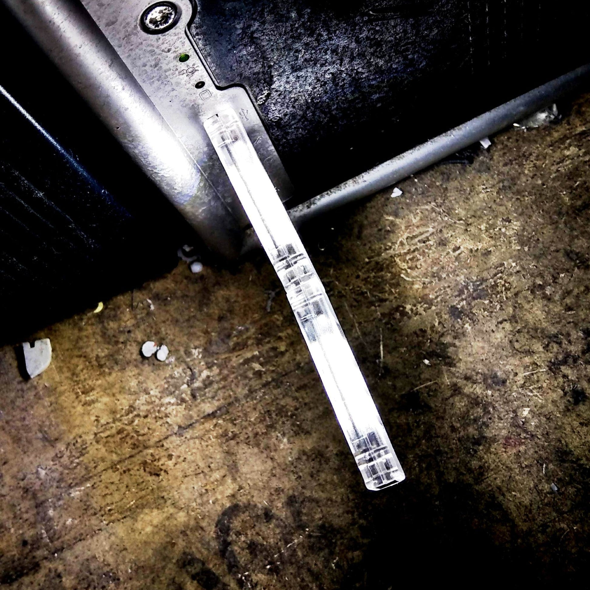 A compact USB LED light plugged into the side of a laptop, brightly illuminating a dark surface.