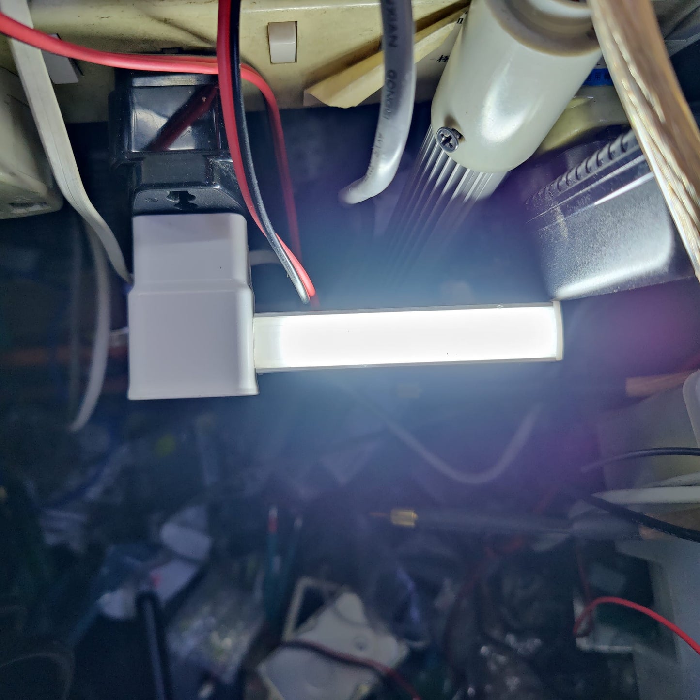 Bright USB LED light bar plugged into adapter illuminating dark space.