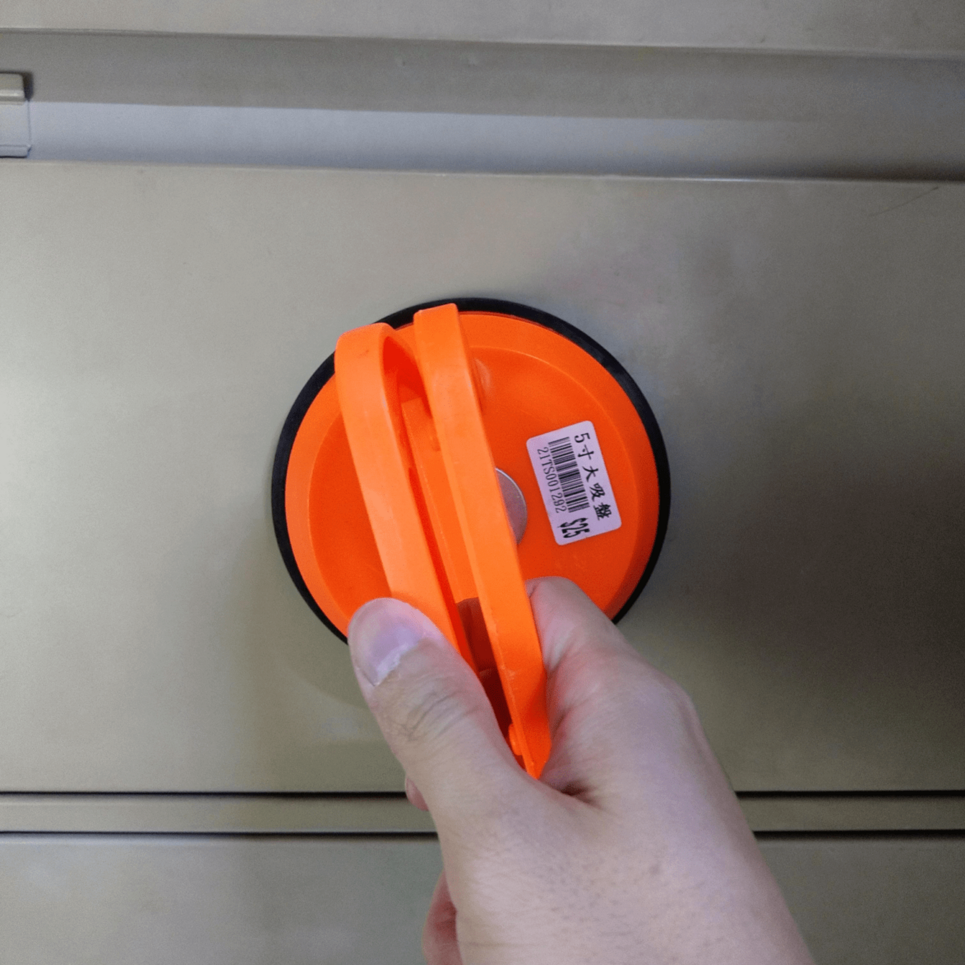 5-Inch Heavy-Duty Suction Cup Lifter & Dent Puller being held with orange grip against a smooth surface.