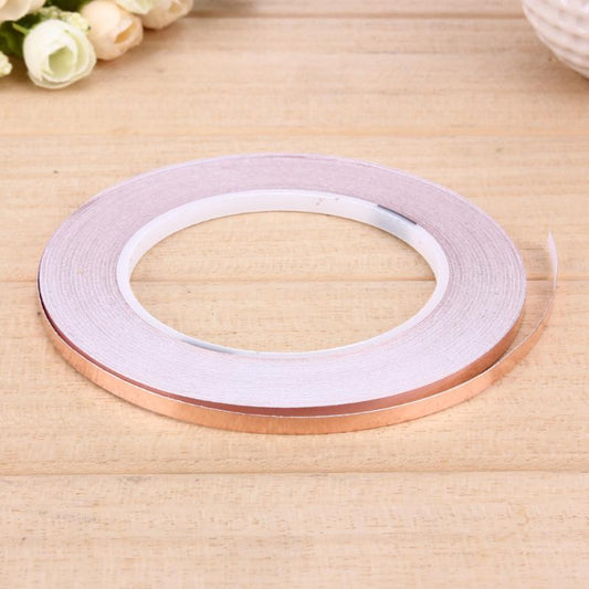 Copper foil tape roll on wooden surface, 5mm x 50m adhesive conductive tape for EMI shielding and repairs.