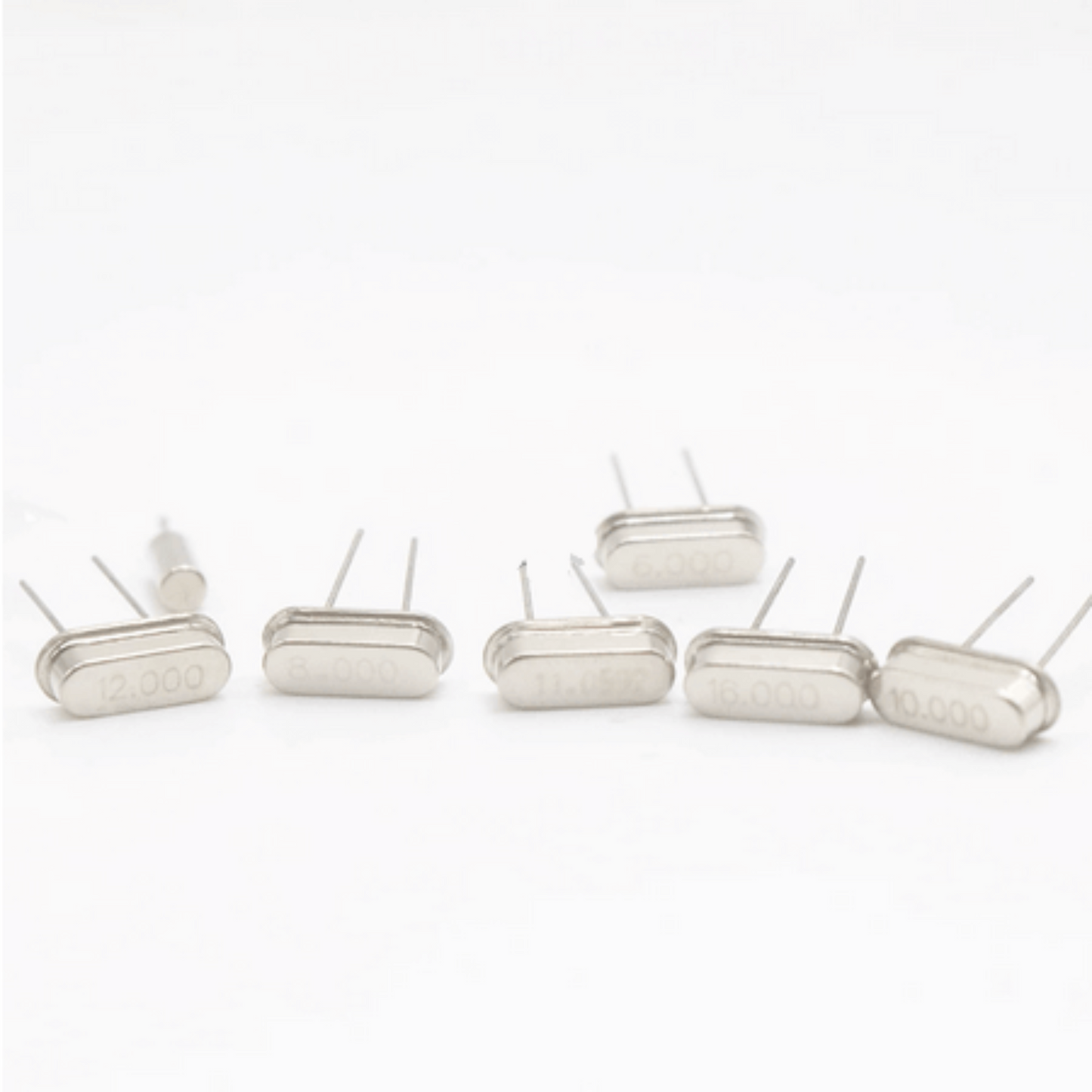 Crystal oscillator components showing frequency values of 12.000, 16.000, and 10.000 MHz in a DIY electronic kit.