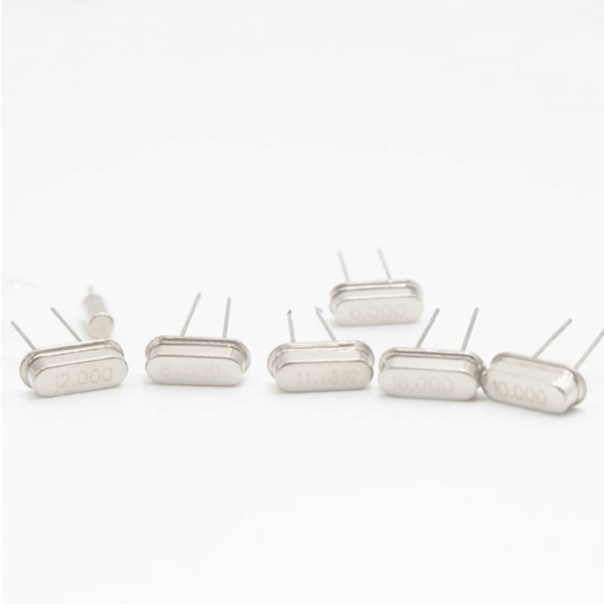 Crystal oscillator components showing frequency values of 12.000, 16.000, and 10.000 MHz in a DIY electronic kit.