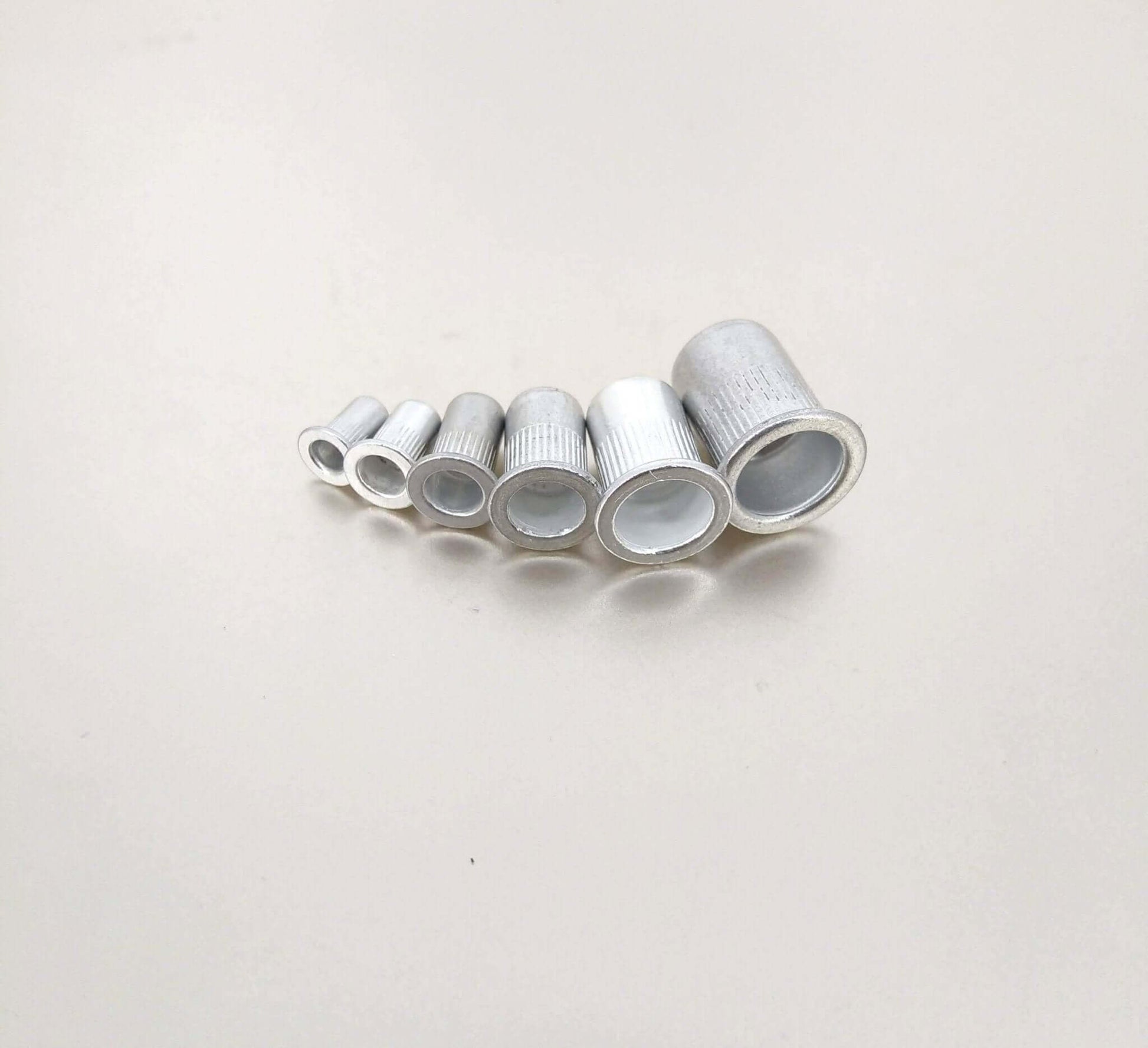Set of six aluminum rivet nuts in various sizes, ideal for creating strong threaded inserts in thin materials.