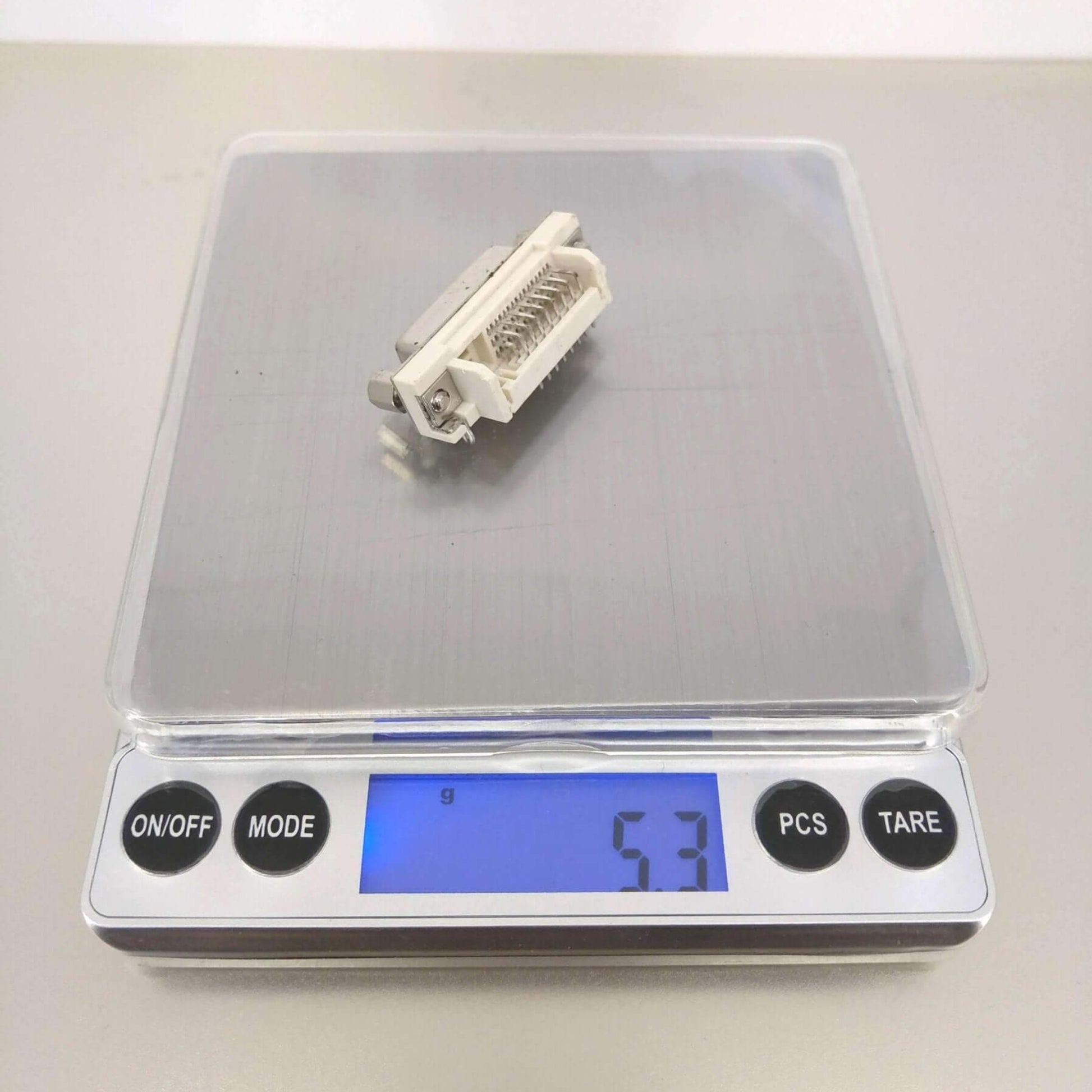 High precision digital pocket scale displaying a weight of 5.3 grams with a small item on the weighing platform.