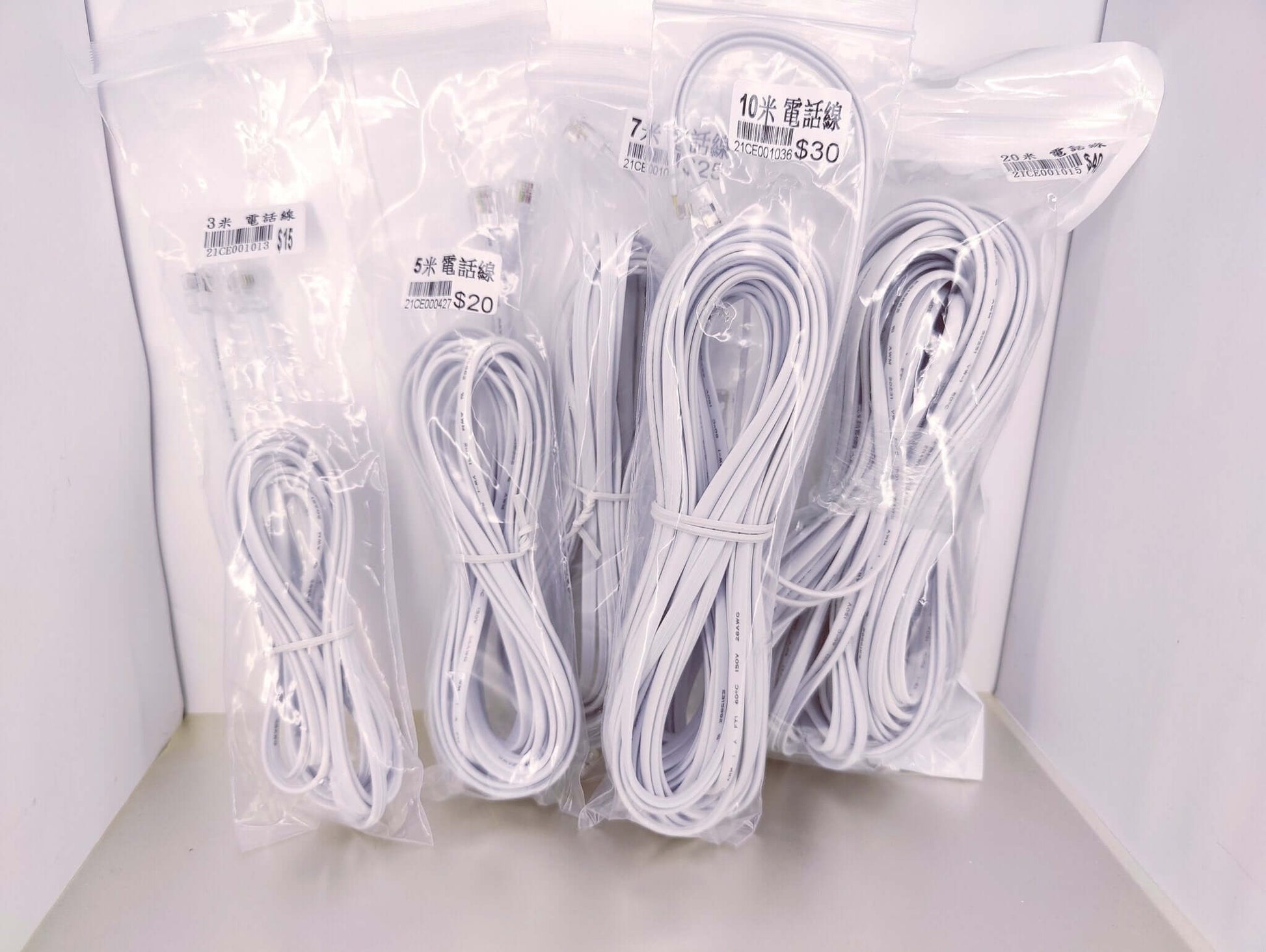 Four packages of white RJ11 telephone extension cables in 3 meter, 5 meter, 10 meter, and 20 meter lengths.