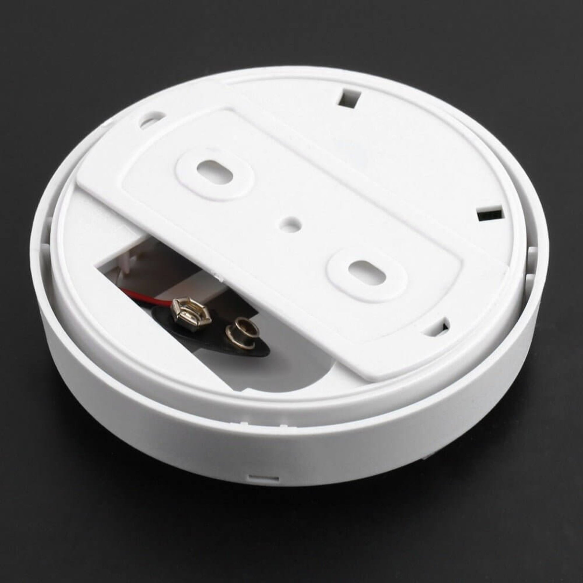Back of a smoke alarm, showing the battery compartment and wiring for easy installation and maintenance.